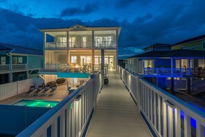 A two-story waterfront property with a covered deck, a pool, and multiple balconies.