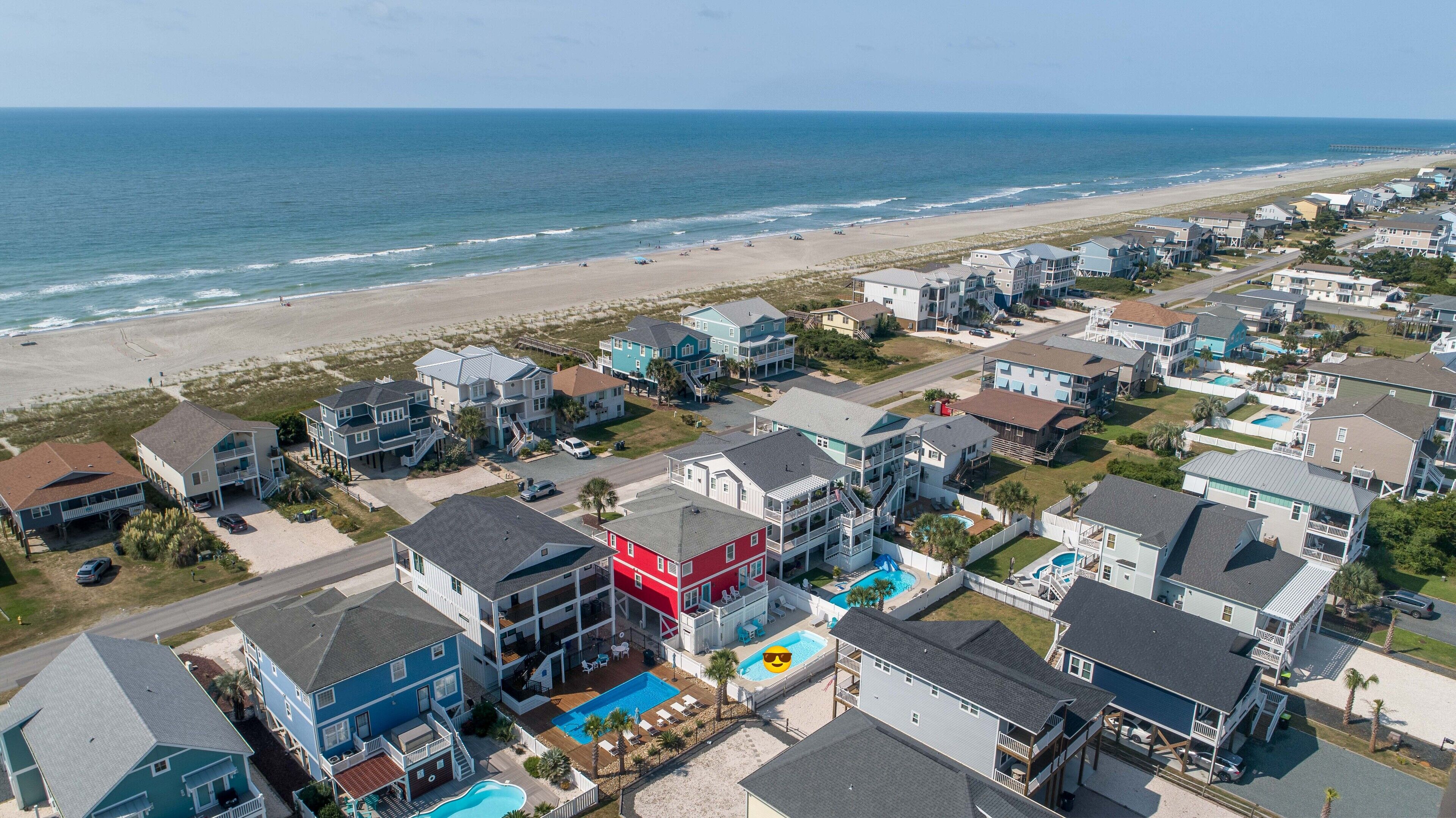A coastal residential area with houses, a beach, and a pier.