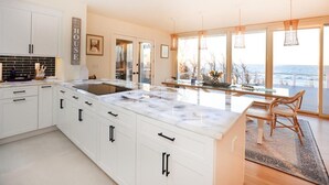 A modern kitchen with white cabinetry, a marble island, and a view of the sea. - Water Front Property with Customized Pool and Spa with private access to the Delaware Bay (Villas)