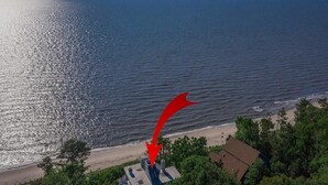 An aerial view of a coastal property with a beach, dense greenery, and a prominent red arrow pointing to a building. - Water Front Property with Customized Pool and Spa with private access to the Delaware Bay (Villas)