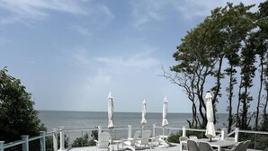 A pool area with lounge chairs and umbrellas, overlooking the sea. - Water Front Property with Customized Pool and Spa with private access to the Delaware Bay (Villas)