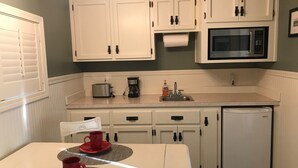 A kitchen with white cabinets, a microwave, a toaster, and a refrigerator. - Beach Comber Cottage (Coupeville)