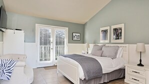 A bedroom with a bed, bedside tables, a chair, and a wardrobe. - Beach Comber Cottage (Coupeville)