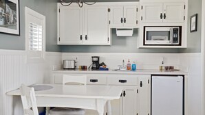 A kitchen with white cabinets, a microwave, a coffee maker, and a refrigerator. - Beach Comber Cottage (Coupeville)