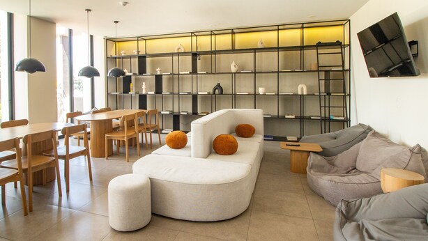 A modern living room with a curved sofa, a grey couch, and a dining area with wooden chairs and a table. - Tribu Coordenada Lafayette (Guadalajara)