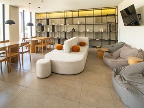 Ein modernes Wohnzimmer mit einer gebogenen Couch, einem grauen Sofa und einem Essbereich mit Holztischen und einem Tisch.