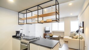 A compact kitchen with a built-in oven, a coffee maker, and a dining area with a round table and chairs. - Tribu Coordenada Lafayette (Guadalajara)