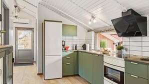 Eine moderne Küche mit grünen Schränken, einem weißen Kühlschrank und einer schwarzen Dunstabzugshaube.
