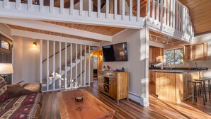 A spacious living area with a wooden dining table, a sofa, and a staircase leading to an upper level. - Spacious, newly remodeled, perfect location w/BBQ, Hot Tub, pool table, SmartTV (Carnelian Bay)