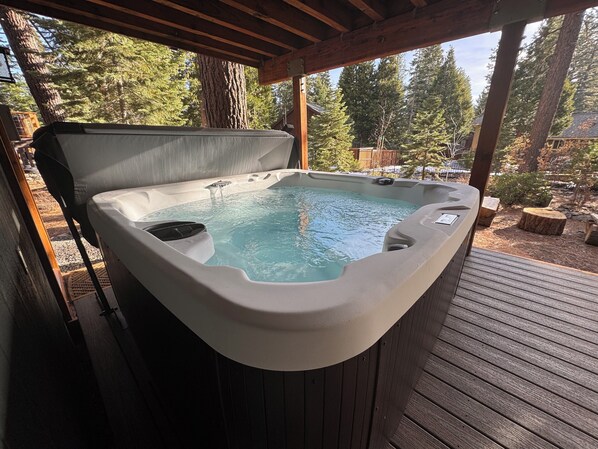A hot tub on a wooden deck with a view of trees.