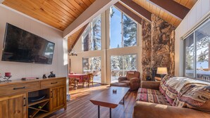 Un salon spacieux doté de parquets en bois, d’un grand téléviseur et d’une cheminée en pierre.