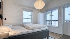 Un dormitorio con cama, ventana, balcón y una lámpara colgante.