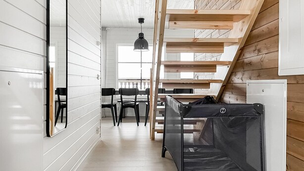 Un interior moderno con una escalera de madera, un comedor y una pequeña cocina.