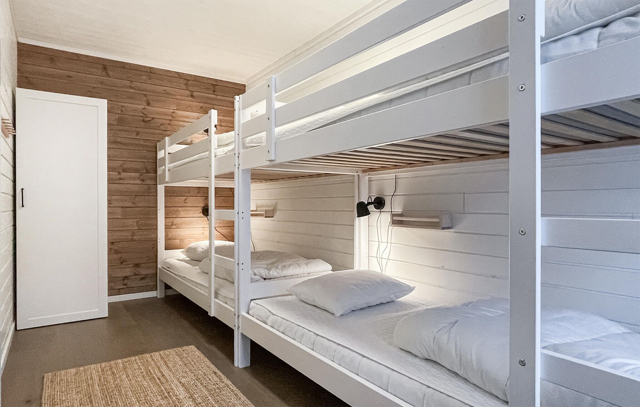 A bunk bed room with a wooden wall and a white door.