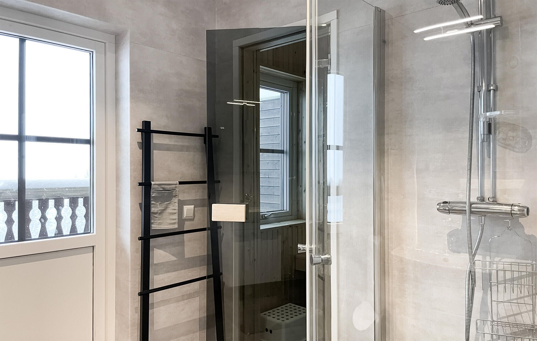 Ein modernes Badezimmer mit Duschkabine aus Glas, Handtuchhalter und einem Fenster mit Blick.
