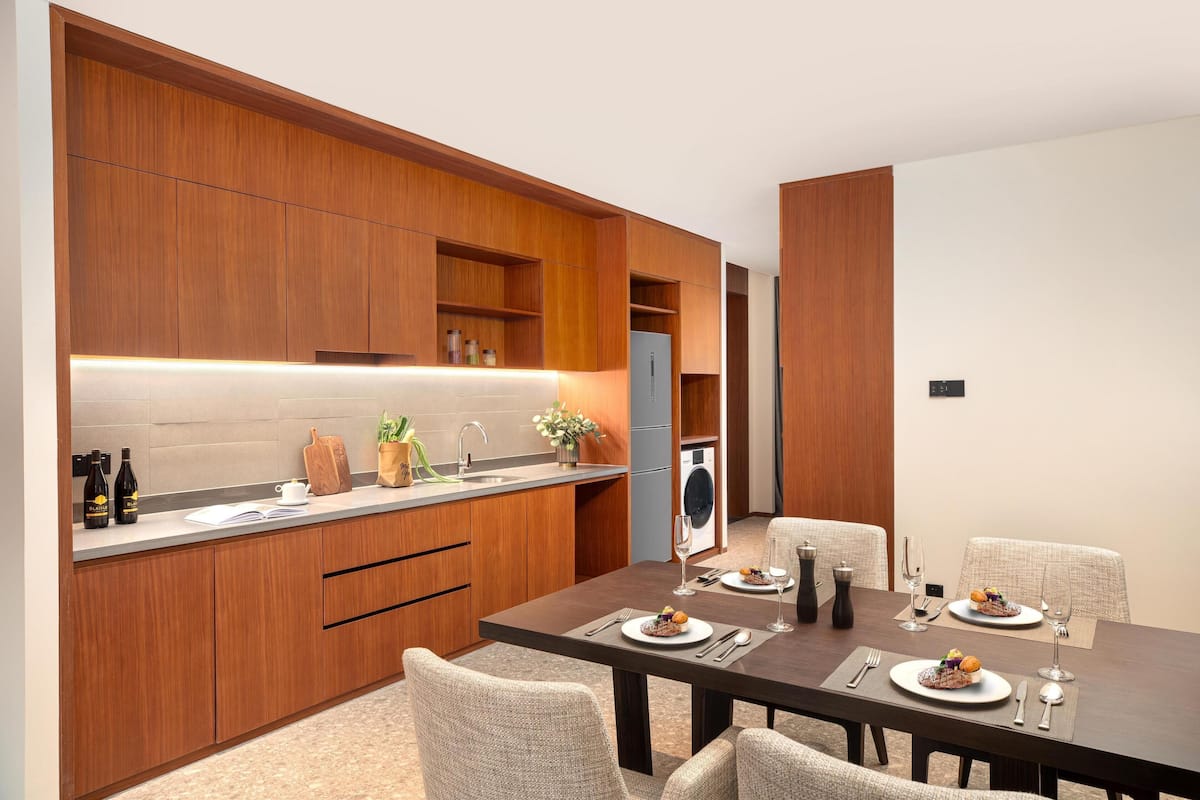 A modern kitchen with wooden cabinets, a built-in oven, and a dining area with a table set for two.