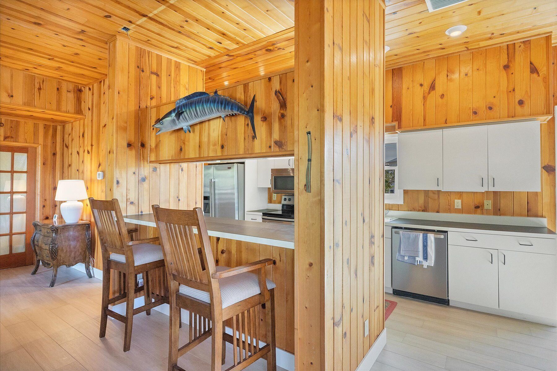 A wooden interior with a dining area, kitchen, and a mounted fish sculpture.