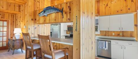 A wooden interior with a dining area, kitchen, and a mounted fish sculpture.