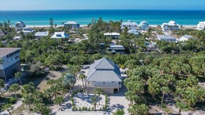 Luftaufnahme eines Küstenresorts mit mehreren Gebäuden, umgeben von üppigen Palmen und freiem Blick auf den Ozean.