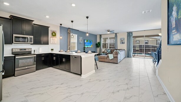 A modern kitchen with dark cabinets, a central island, and a dining area with a view.