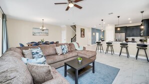 A spacious living room with a large sectional sofa, a coffee table, and a ceiling fan.