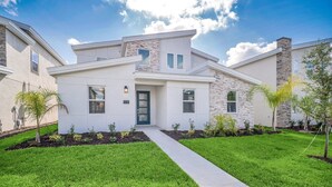 A modern two-story house with a stone facade, a front porch, and a well-maintained lawn.