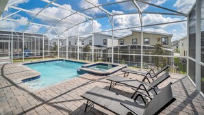 A covered outdoor swimming pool with lounge chairs and a hot tub.