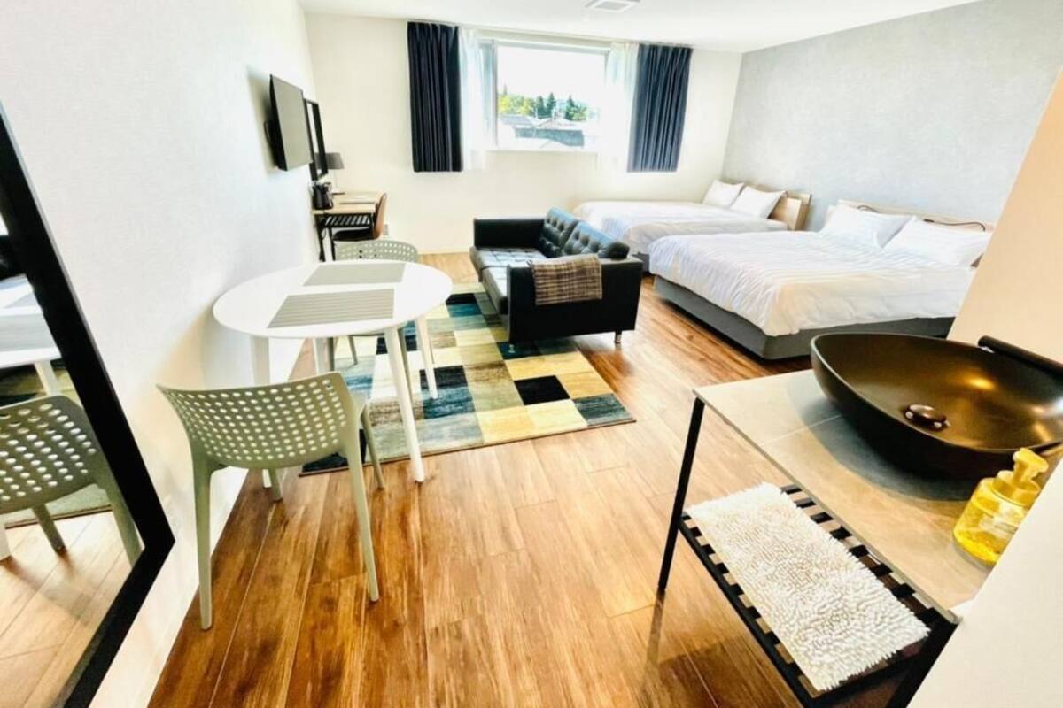 Habitación de hotel con cama, escritorio, silla, sofá, televisor y ventana.