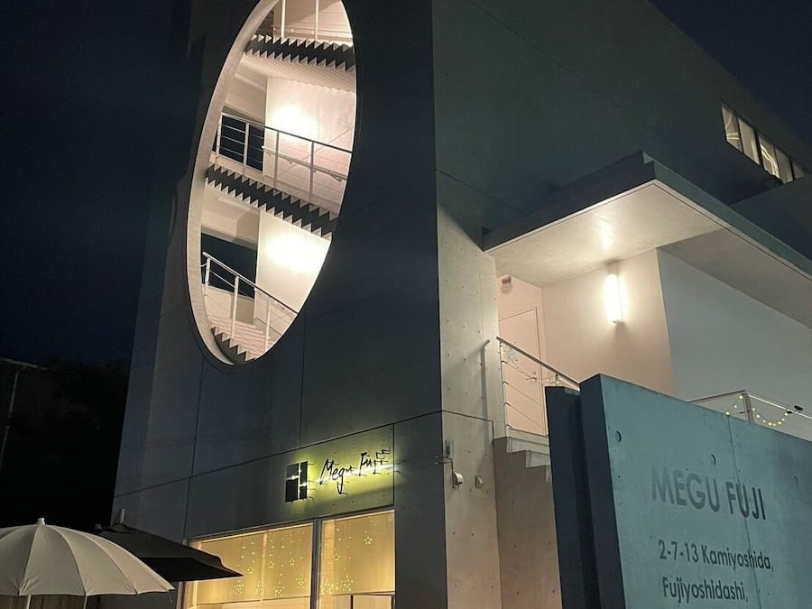 Un edificio moderno con un amplio ventanal circular y un letrero para el restaurante 'MEGU FUJI'.