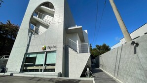 Un bâtiment moderne doté d’une architecture originale, avec une grande fenêtre en arc de cercle et un escalier menant à un niveau supérieur.