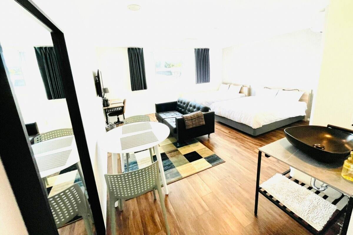 Habitación de hotel con cama, sofá, mesa de comedor y zona de cocina.