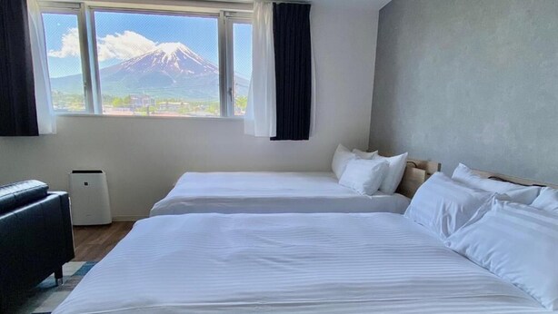 Une chambre d’hôtel avec deux lits, une fenêtre donnant sur une montagne, un bureau et une chaise.