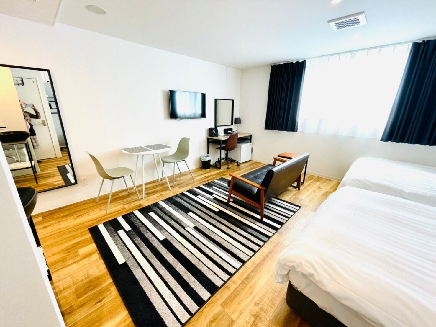 Habitació d'hotel moderna amb un llit gran, una escriptori amb una cadira, una taula petita i una televisió.