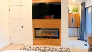 Une chambre moderne avec une cheminée, un lit et une vue sur le salon.