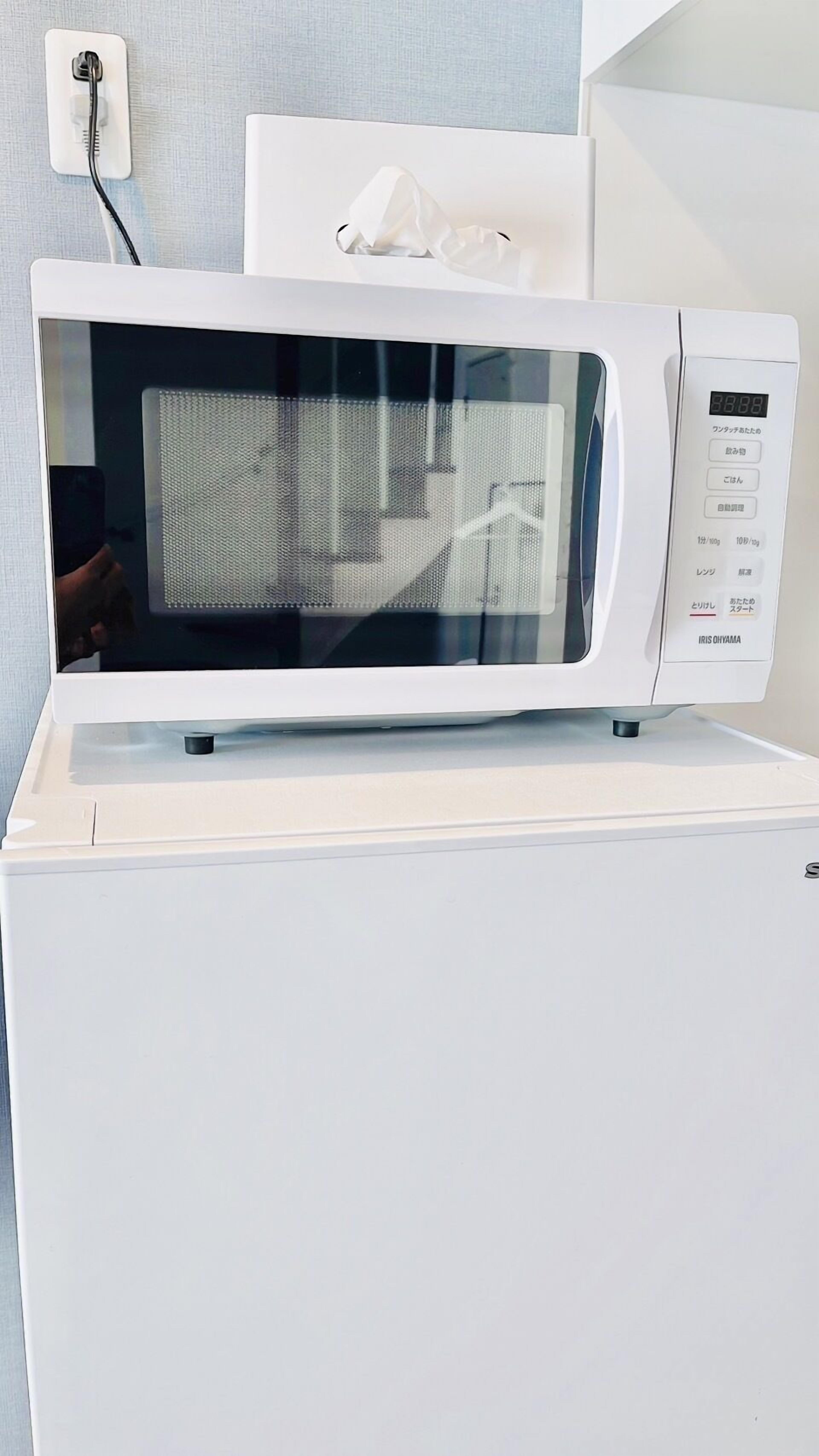 A white microwave oven with a digital display, placed on a white appliance.