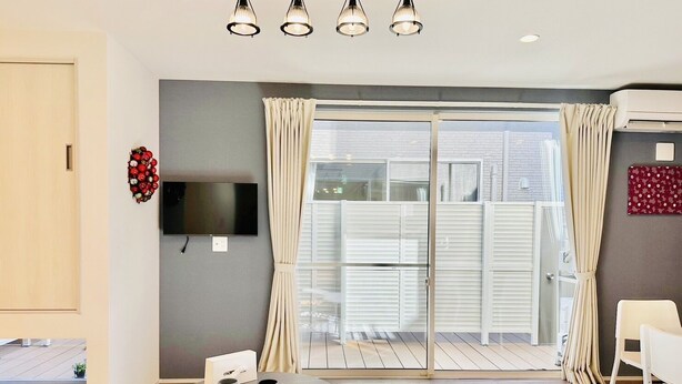 A modern living room with a flat-screen TV, two round tables, a sofa, and a sliding glass door leading to an outdoor area. - Megu Fuji Plus+ (Fujiyoshida)