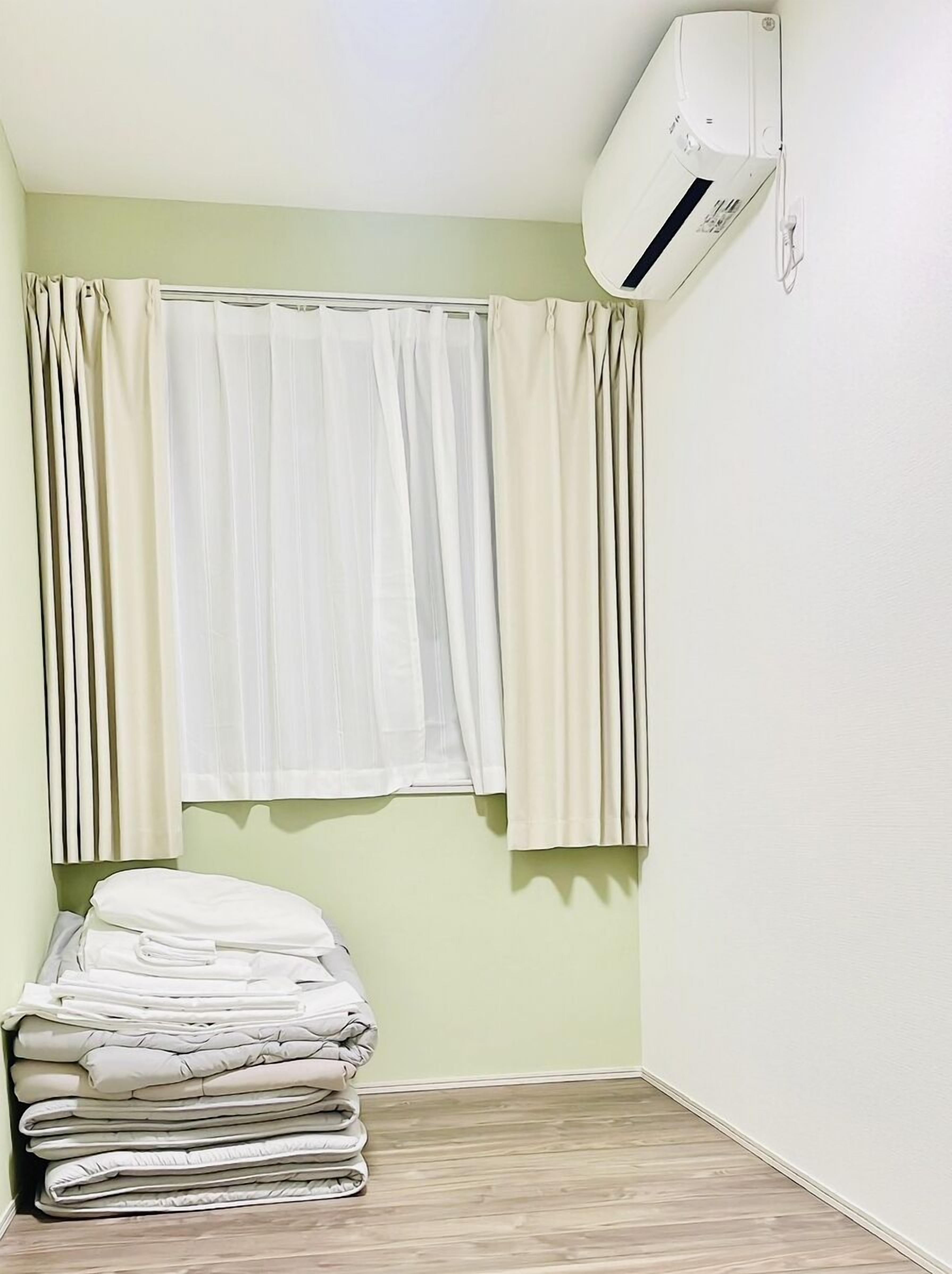 A room with a bed, a window with curtains, and an air conditioning unit.