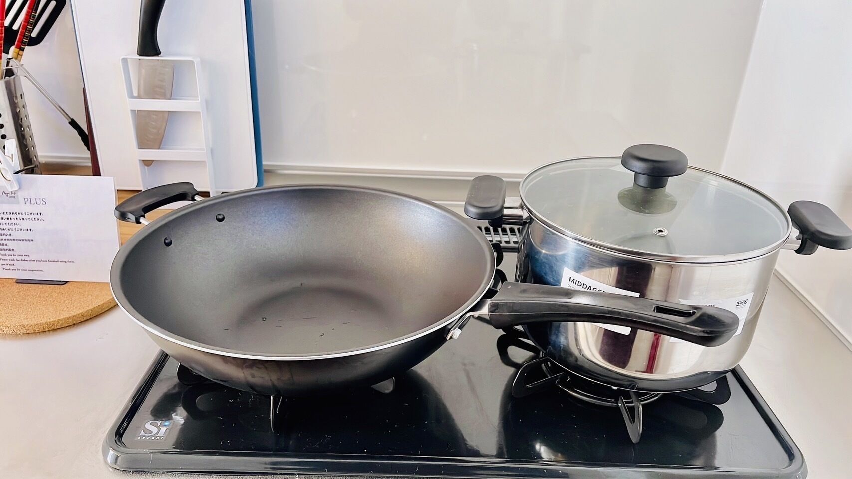 Une cuisine équipée d’une cuisinière, d’un wok et d’une casserole.