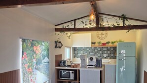 A kitchen with wooden beams, a refrigerator, a microwave, and a dining area with chairs and a table. - Rose Inn (Seoul)