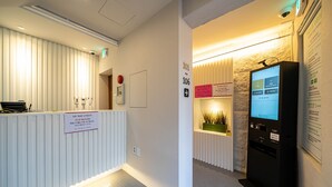 A reception area with a reception desk, a digital information kiosk, and directional signs. - Rose Inn (Seoul)