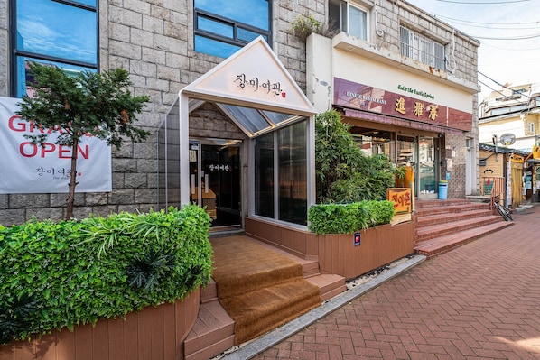A hotel entrance with a covered entrance, a sign indicating 'OPEN', and a nearby restaurant with a visible sign.