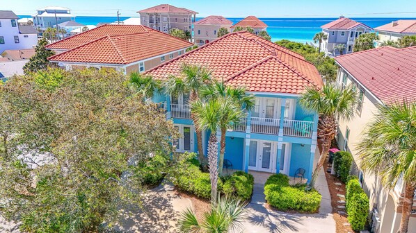 A coastal residential area with houses featuring red-tiled roofs and balconies overlooking the sea. - Coco's Cabana - Steps to Beach! (Panama City Beach)
