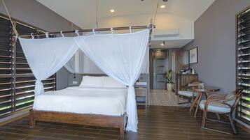 Un dormitorio con cama de madera, ventilador de techo y vistas al exterior a través de amplios ventanales.