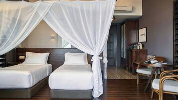 A hotel room with two beds, a canopy bed, a dining area with chairs, and a small table.