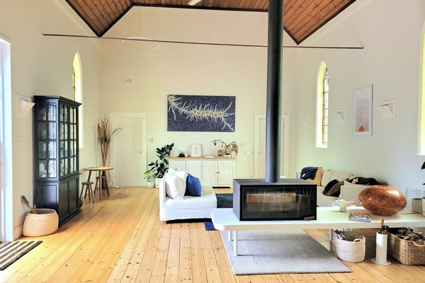 Open plan living room with soaring ceilings and double sided wood burner