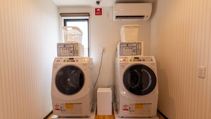 A laundry room with two stacked washing machines, a window, and an air conditioning unit. - HOTEL R9 The Yard Fujioka (Fujioka)