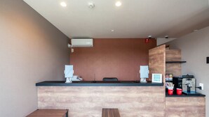 A reception desk with a wooden counter, a small table, and a coffee machine. - HOTEL R9 The Yard Fujioka (Fujioka)