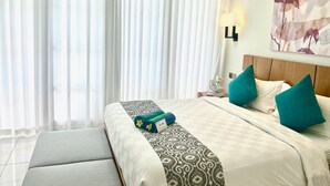 Hotelkamer met een groot bed, een bankje, een nachtkastje en een wandlamp.