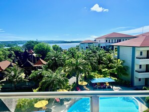 Un complexe hôtelier doté d’une piscine, de palmiers et offrant une vue sur la mer.
