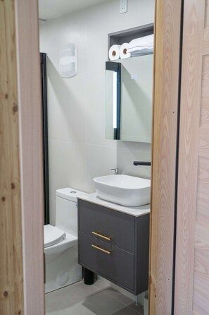 A modern bathroom with a white sink, dark cabinet, and a mirror above the sink.